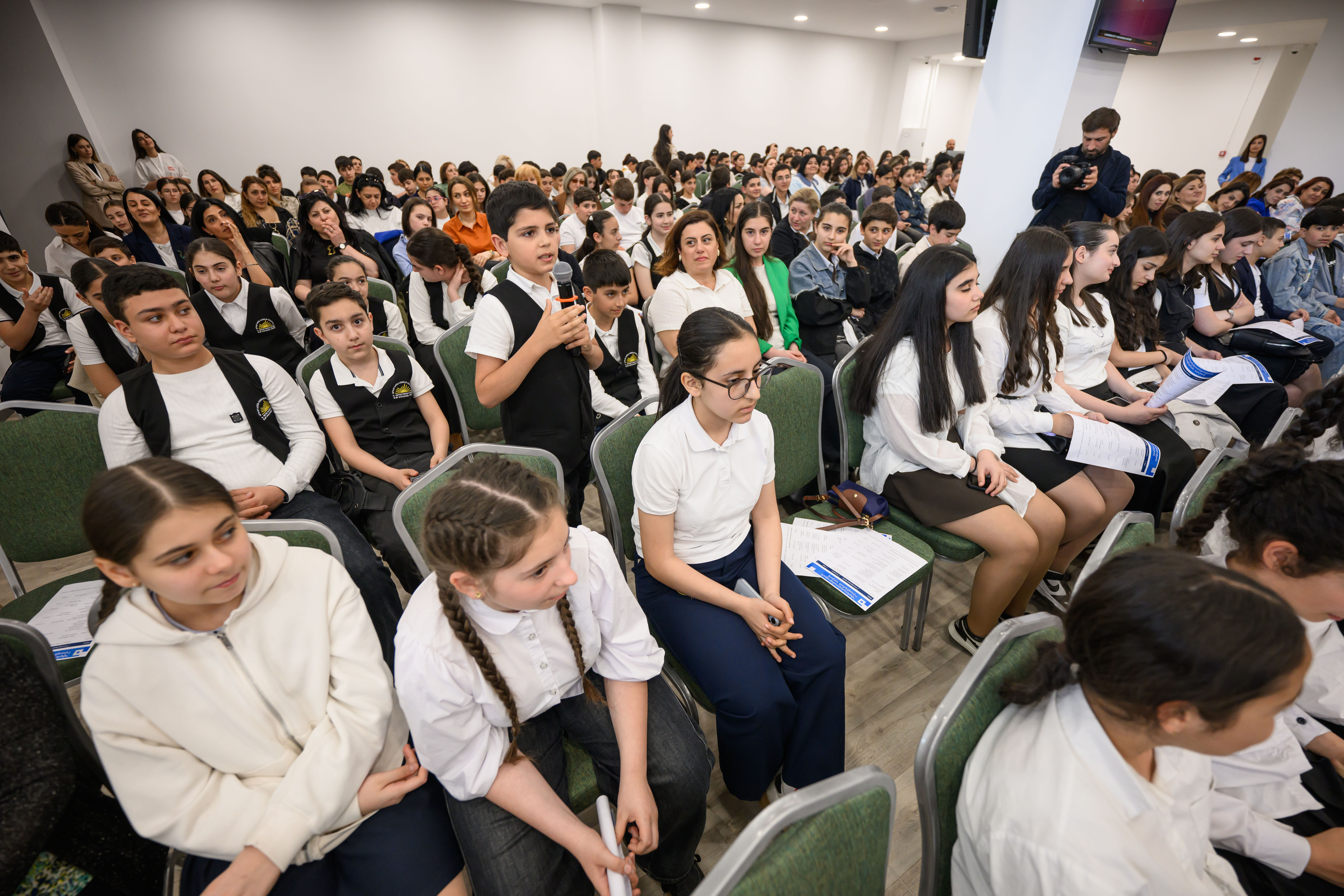 Children are sitting, one of them is asking a question
