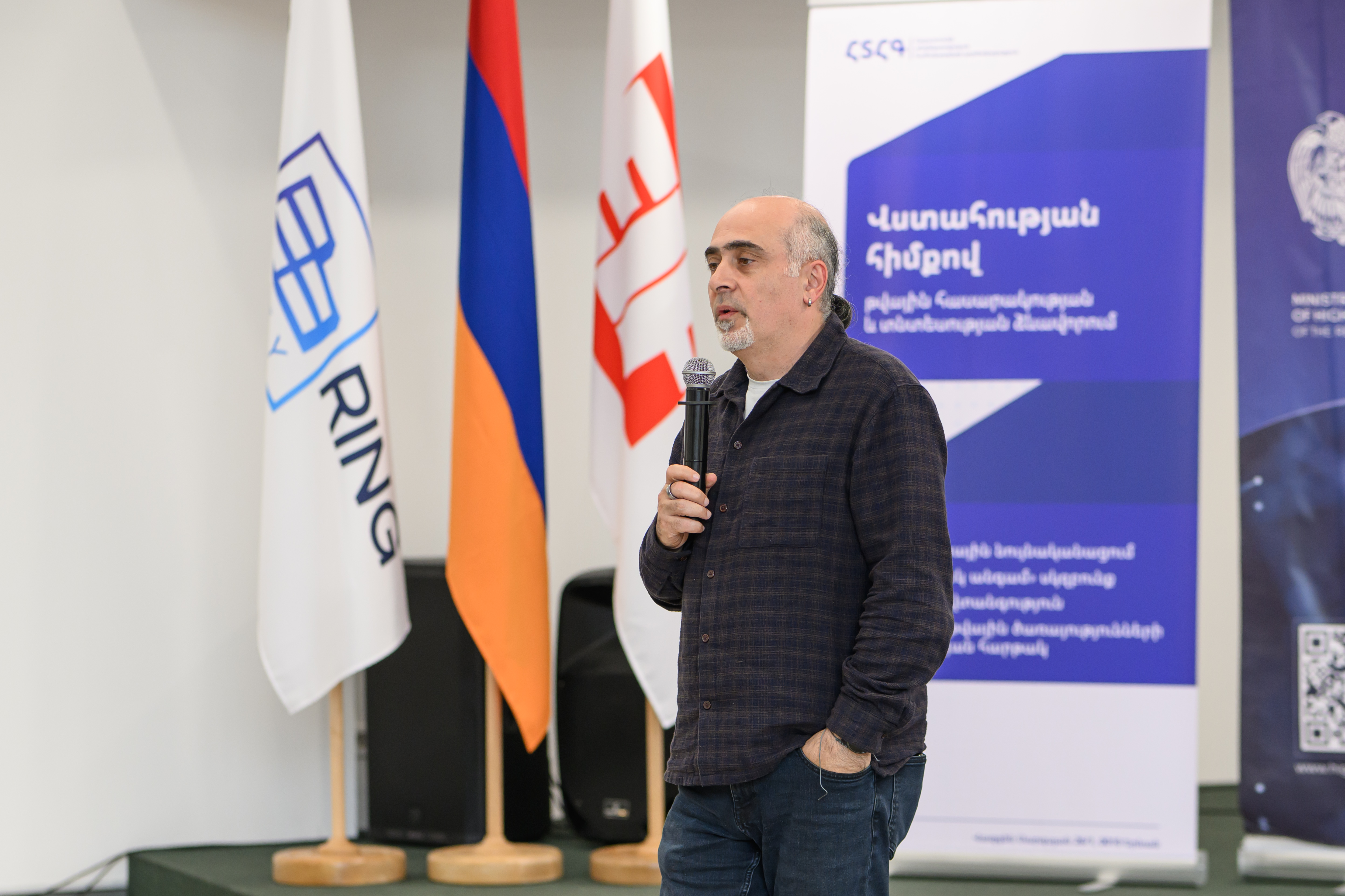 Samvel Martirosyan is speaking, flags in the background
